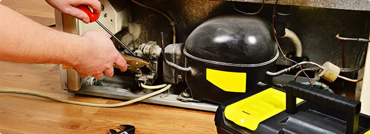 Refrigerator repair technician fixing the compressor and wiring in Green Valley, AZ