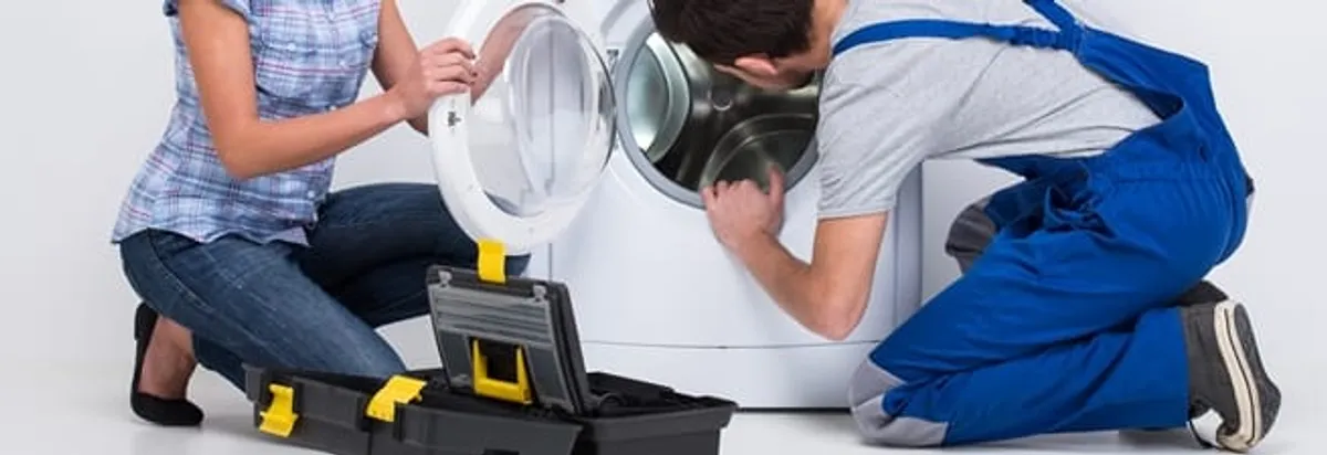Washer repair technician inspecting a front-load washing machine with tools in Tucson, AZ