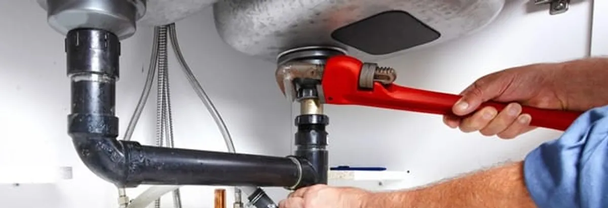Garbage disposal repair technician tightening the sink drain and disposal connection in Tucson, AZ