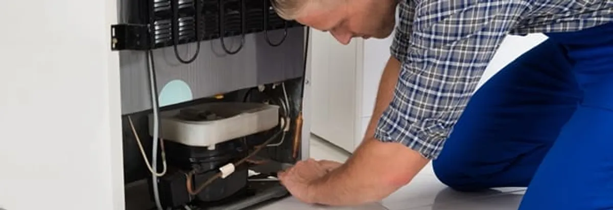 Refrigerator repair technician servicing the compressor and condenser area in Tucson, AZ