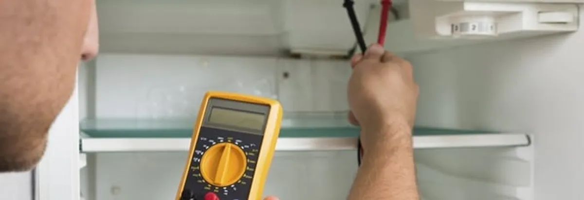 Refrigerator repair technician testing electrical components with a multimeter in Tucson, AZ